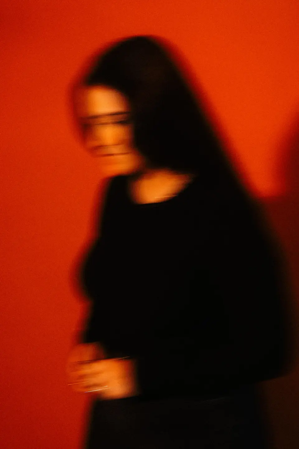 Motion-blurred figure in black against a red wall.
